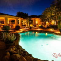 backyard with pool illuminated with landscape lighting